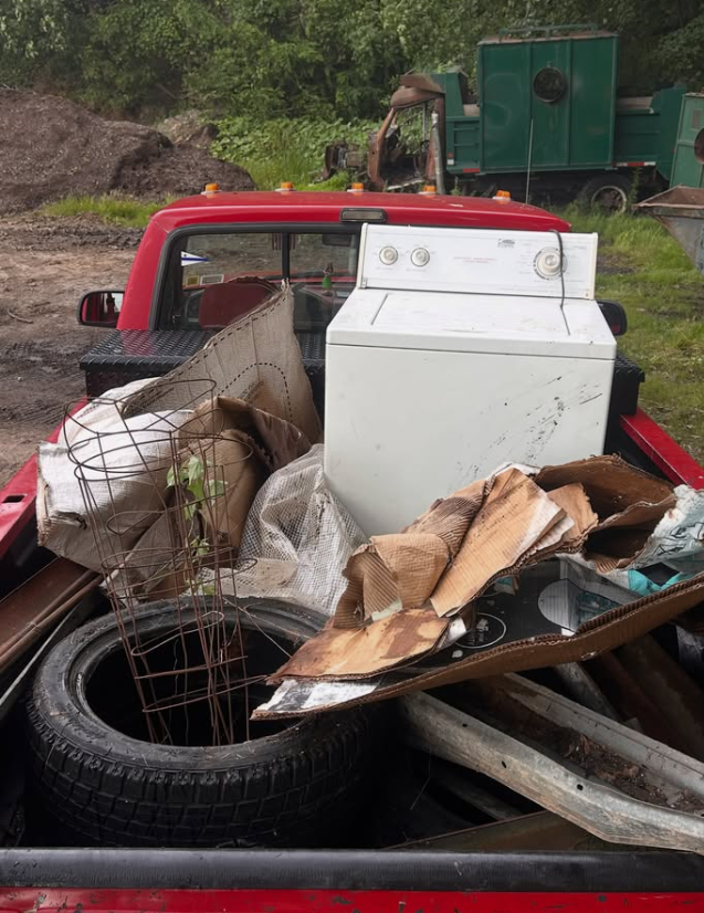 Truck bed loaded with a washer, tires, and household junk
